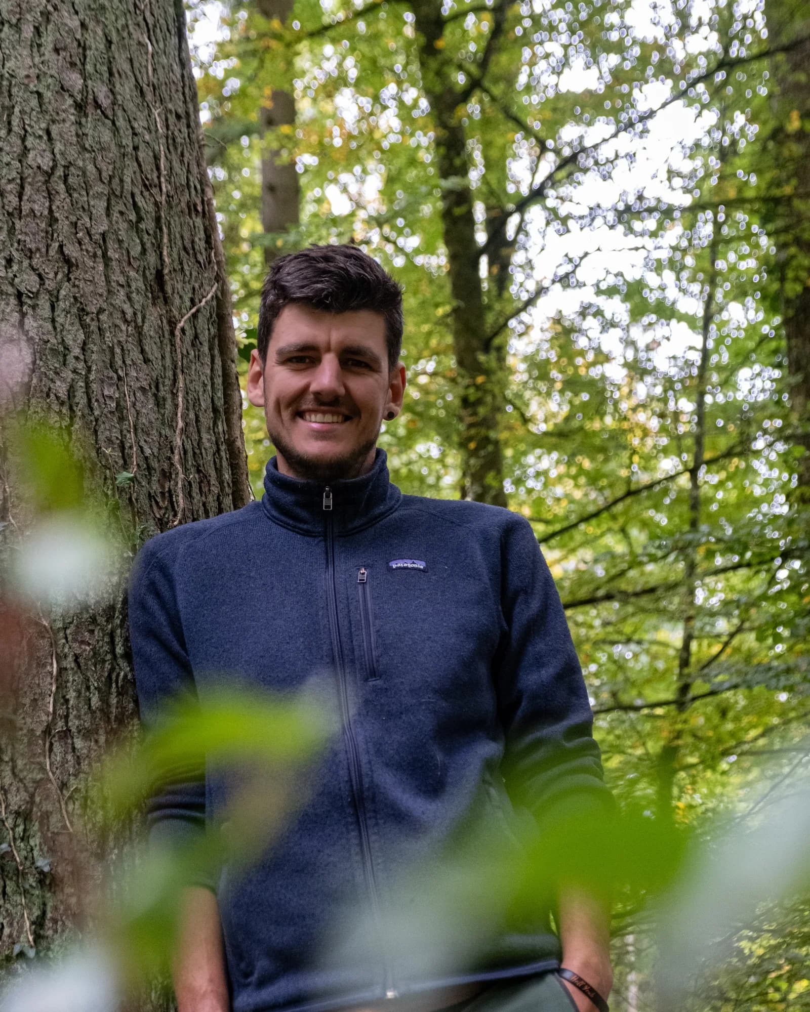 Nicolas Fischer, im Wald an einen Baum gelehnt